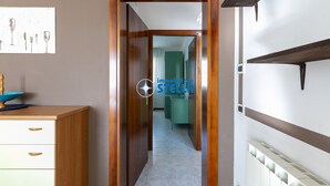Un pasillo con una puerta de madera, un radiador y un cuadro en la pared.
