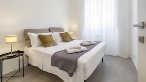 A neatly arranged hotel room with a bed, bedside tables, and a window with curtains. - Great Opera at Via Palermo (Roma)