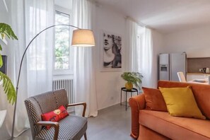 A living room with a sofa, a chair, a lamp, a radiator, a plant, and a wall with a picture. - Great Opera at Via Palermo (Roma)