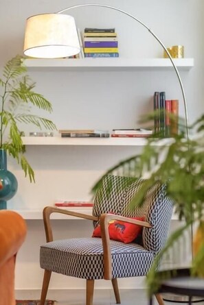 A modern living room with a patterned armchair, a floor lamp, and a bookshelf with books. - Great Opera at Via Palermo (Roma)