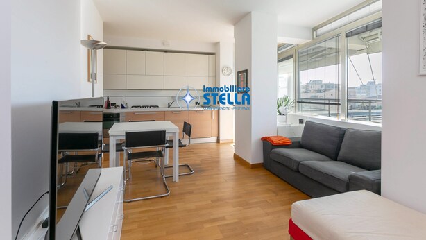 Un appartement moderne comprenant une cuisine, un coin repas et un salon avec une grande fenêtre.