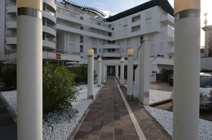Ein mehrstöckiges Hotel mit Innenhof, weißen Säulen und einem gepflasterten Weg.