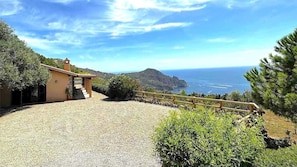 A coastal property with a gravel driveway, a wooden fence, and a view of the sea. - The Dot of Porto Ercole (Porto Santo Stefano)