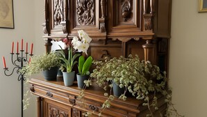 A wooden cabinet with carved details, a candelabra with red candles, and various potted plants. - The view of the Castle (Cereseto)