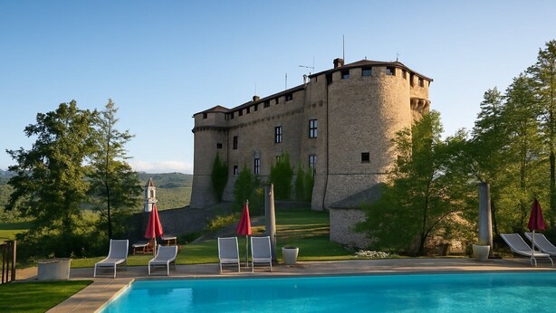 A castle with a swimming pool, lounge chairs, and umbrellas. - The view of the Castle (Cereseto)