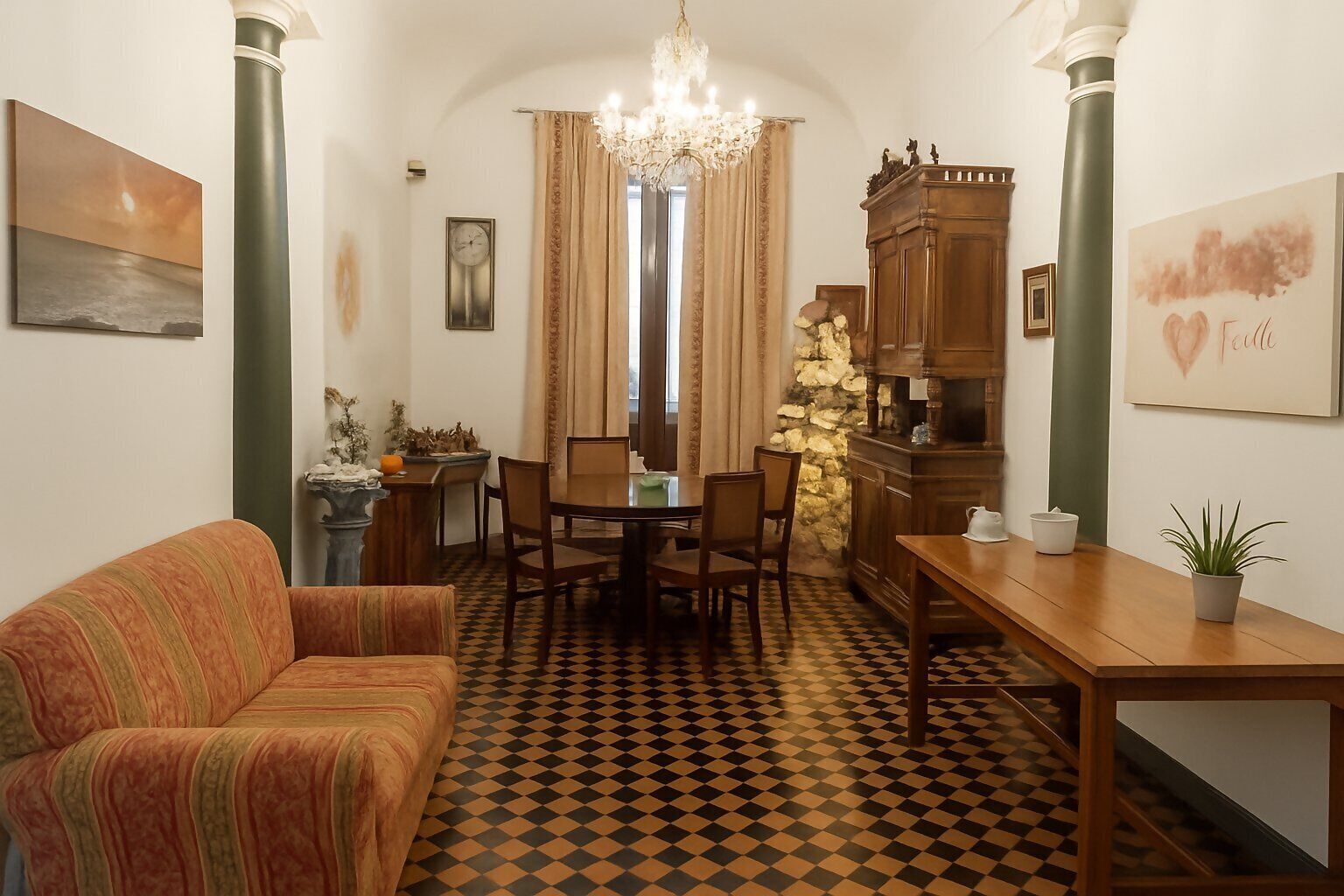 Un salón acogedor con sofá, mesa de comedor, sillas, una araña y suelo a cuadros.