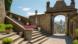 A stone staircase leading to a building with an archway, surrounded by potted plants and a clear sky. - The view of the Castle (Cereseto)