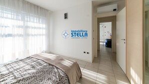 Una camera d'albergo con un letto, un condizionatore fissato al muro, una porta che dà su un corridoio e un logo sulla parete.