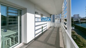Un balcone con una porta vetrata, un tavolo con sedie e vista sul mare.