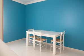 A white table and four chairs in a room with a blue wall and white floor. - Vacation Home Mother Angela (Letojanni)