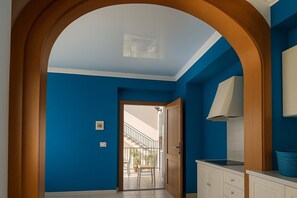 A hallway with a blue wall, a wooden door, and a view into a balcony area. - Vacation Home Mother Angela (Letojanni)