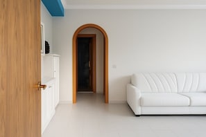 A room with a white sofa, a wooden door, and a tiled floor. - Vacation Home Mother Angela (Letojanni)
