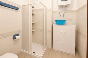 Ein Badezimmer mit Dusche, Toilette und einem Schrank mit einem blauen Waschbecken.