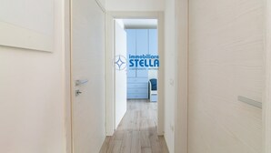 Een gang die leidt naar een kamer met een blauwe kast en een bed.