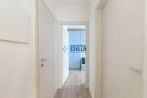 Ein Flur, der zu einem Zimmer mit einem blauen Kleiderschrank und einem Bett führt.
