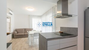 Een moderne keuken met een geïntegreerd eiland, witte kasten en een roestvrijstalen afzuigkap.