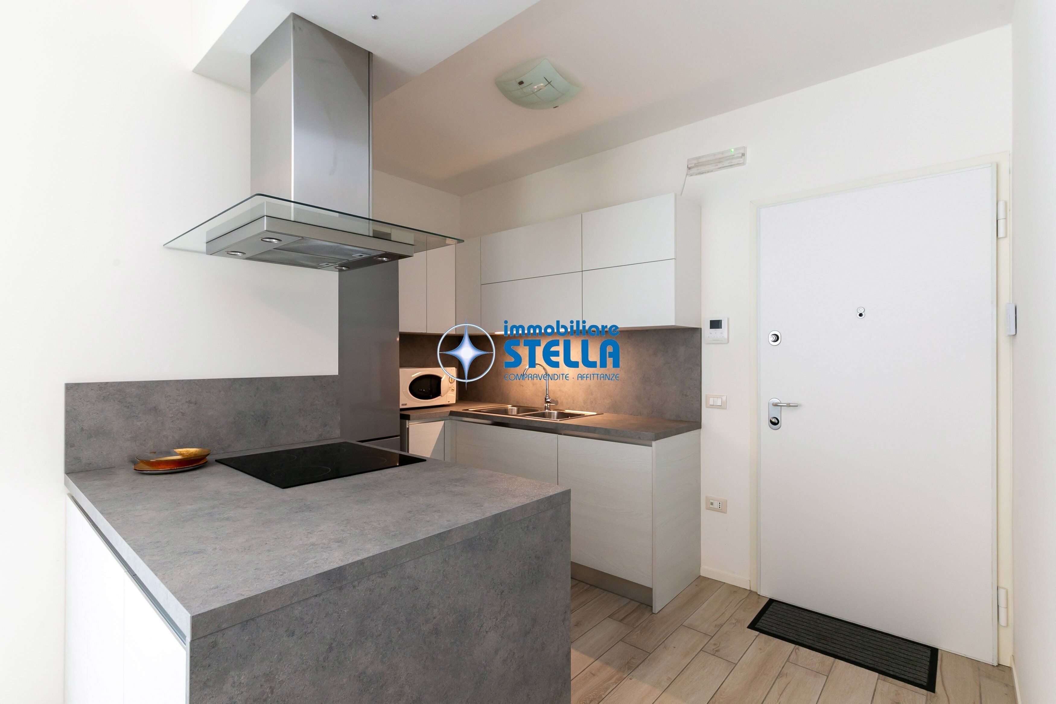 Cocina moderna con una isla de vidrio, campana extractora de acero inoxidable y una puerta blanca.