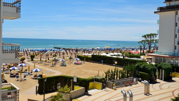 Un complexe hôtelier de bord de mer doté d’une plage de sable, de parasols et offrant une vue sur la mer.