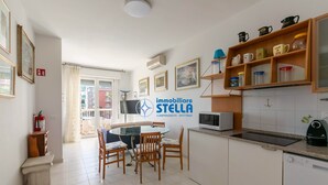 Une cuisine moderne avec un coin repas, des meubles blancs et le logo de « immobiliare STELLA ».