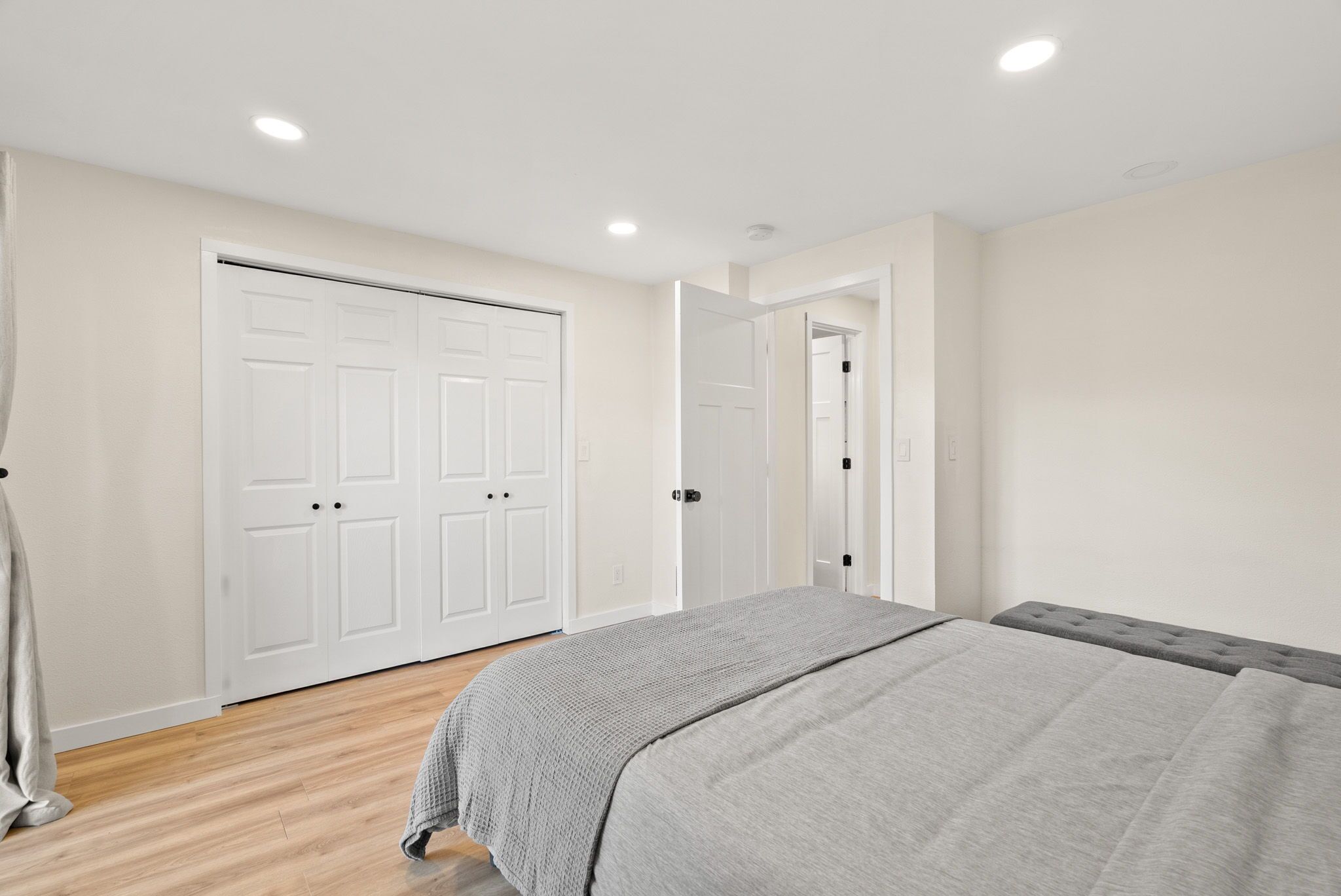 A bedroom with a bed, a wardrobe, and a door leading to another room.