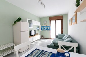 Un salon avec un canapé, un téléviseur, une table à manger sur laquelle se trouve une tasse de café et une bibliothèque.