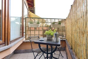 A small outdoor patio with a table, chairs, a coffee pot, and potted plants. - 4BNB - San Lorenzo Spacious Apartment (Rome)