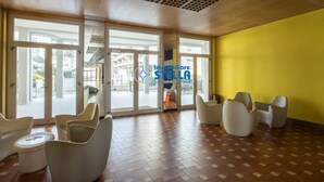Eine geräumige Lobby mit modernen Sitzgelegenheiten, großen Glasüren, die nach draußen führen, und einer gelben Akzentwand.