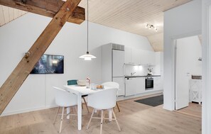 Eine moderne Küche mit weißen Schränken, einem eingebauten Backofen und einer Hängelampe.
