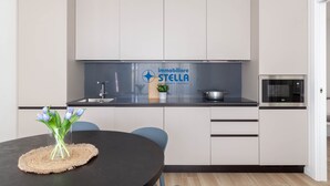 Una cuina moderna amb armaris blancs, tauleig negre, un rentaplatets d'acer inoxidable i un microones.
