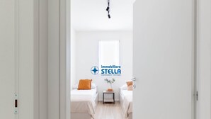 Una habitació d'hotel amb dos llits, una taula petita, una finestra i un logotip a la paret.