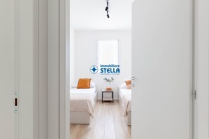 Una habitació d'hotel amb dos llits, una taula petita, una finestra i un logotip a la paret.