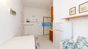 Ett kompakt bostadsutrymme med ett litet kök, en matplats och en soffa.