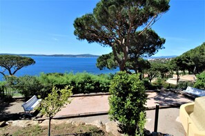 Um parque costeiro com um banco, árvores e vista para o mar.