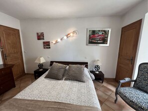 A bedroom with a bed, two nightstands, a chair, a door, and wall decorations. - VILLA WITH BEAUTIFUL SEA VIEW AND SWIMMING POOL TO RENT FOR 8 PEOPLE IN SAINTTE-MAXIME (STE MAXIME)