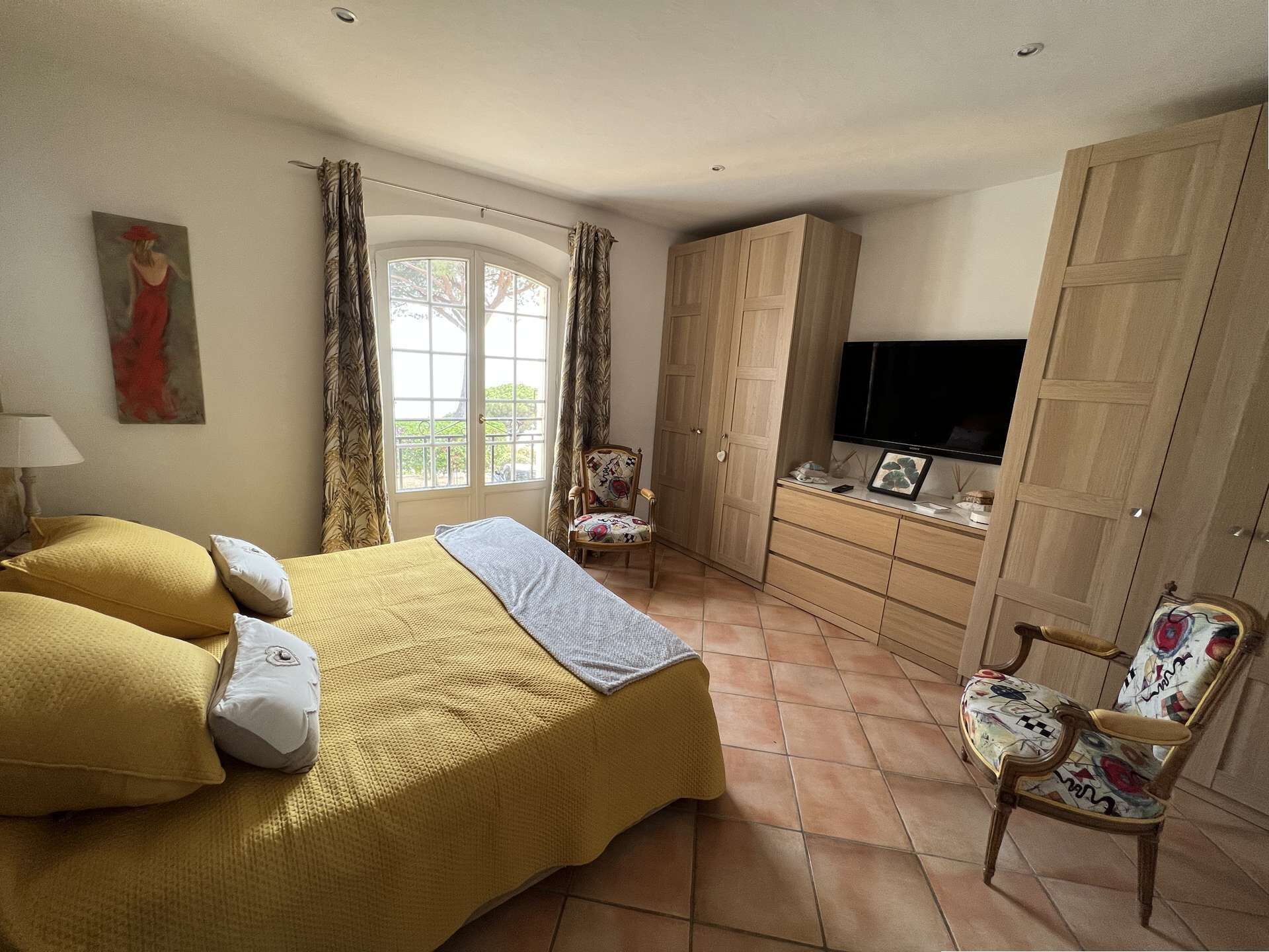 Un dormitorio con cama, una silla, televisor y armario.