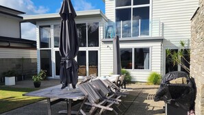 Une terrasse avec une table et des chaises, un parasol et un barbecue.