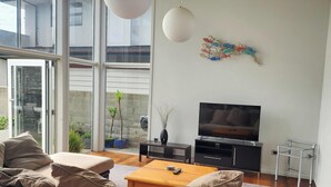 Un salon moderne avec un canapé, un téléviseur et de grandes fenêtres.