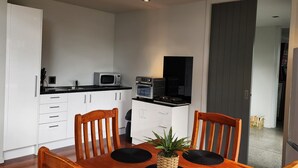 Une cuisine moderne avec des meubles blancs, un four à micro-ondes et une machine à café.