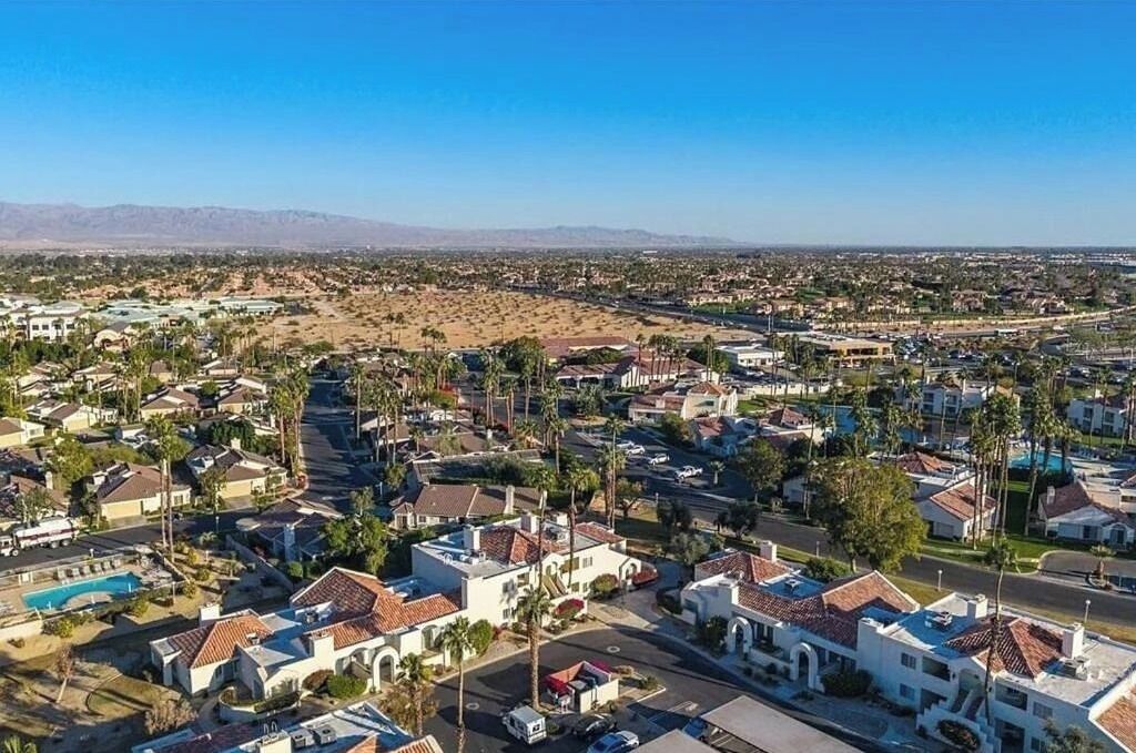 Un quartier résidentiel avec des maisons, des rues et une chaîne de montagnes visible au loin.