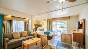 Una camera d'albergo con un divano, un letto, una scrivania, una sedia e un televisore.