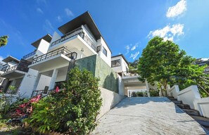 A modern multi-story residential building with a flat roof, balconies, and a paved driveway. - Bangpor Seaview Nice Villa (Koh Samui)