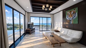 A modern living room with a white sofa, a wooden coffee table, a TV on a wooden stand, and a large window with a view of the ocean. - Bangpor Seaview Nice Villa (Koh Samui)