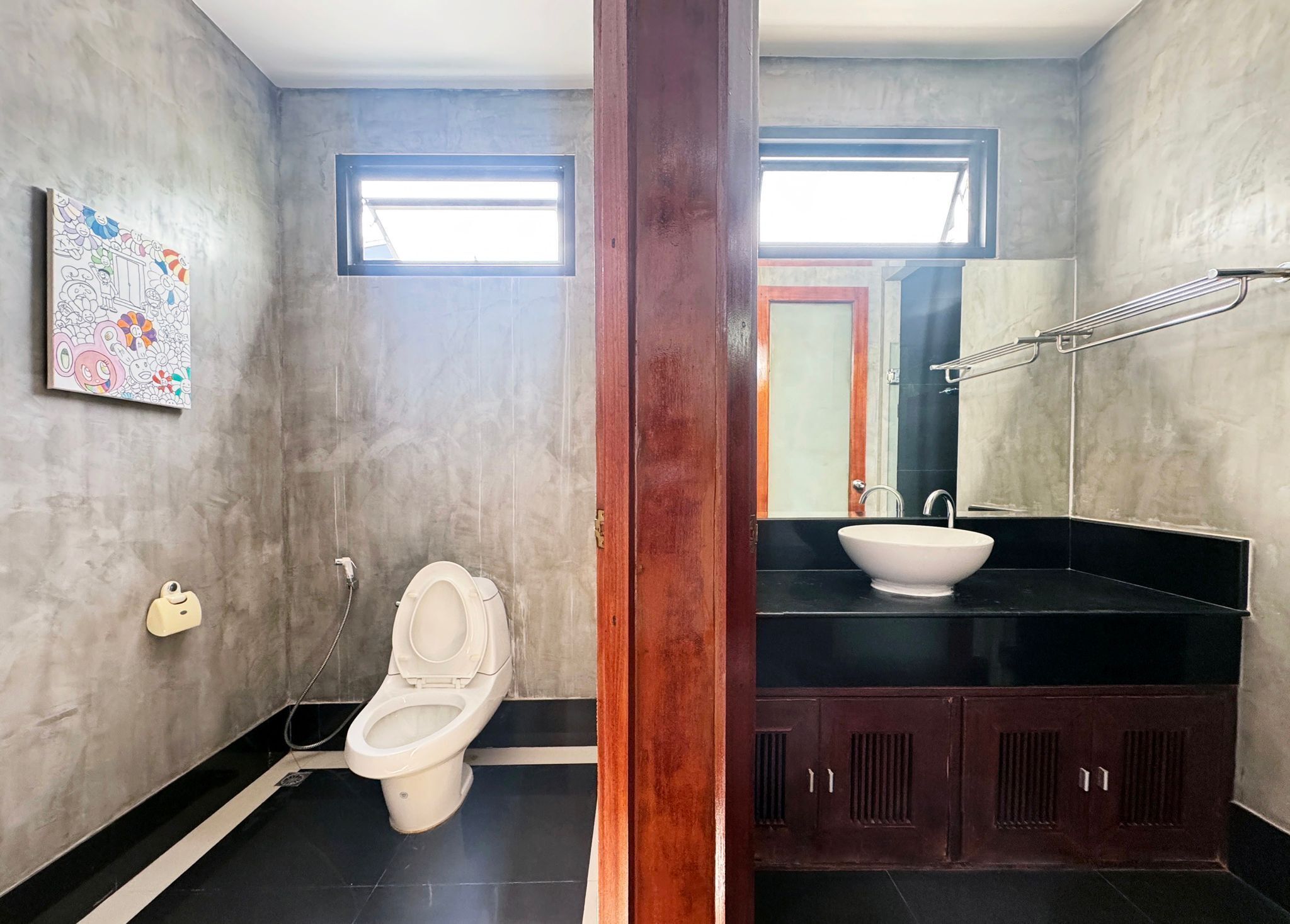 A bathroom with a toilet, a sink, a mirror, and a window.
