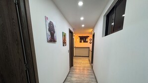 A hallway with a wooden door, white walls, and a patterned floor. - HERMOSO APARTAMENTO EN LAURELES ESTADIO (Medellín)