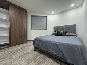 A bedroom with a bed, a wardrobe, a window, and a headboard. - HERMOSO APARTAMENTO EN LAURELES ESTADIO (Medellín)