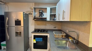 A compact kitchen with a built-in oven, a refrigerator, a coffee maker, and a sink. - HERMOSO APARTAMENTO EN LAURELES ESTADIO (Medellín)