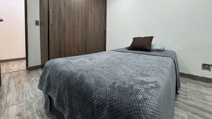A bedroom with a bed, a wardrobe, and a door. - HERMOSO APARTAMENTO EN LAURELES ESTADIO (Medellín)
