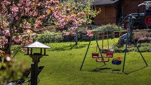 Un'area verde con altalene, un gazebo e un trattore sullo sfondo.