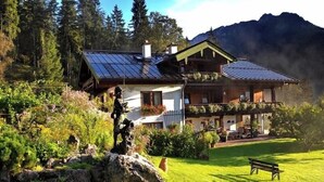 Un chalet con tetto spiovente, un balcone e una statua di pietra in primo piano.