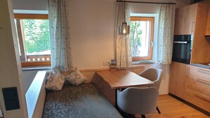 Una kitchenette acogedora con horno integrado, una mesa de madera y un banco con cojines.